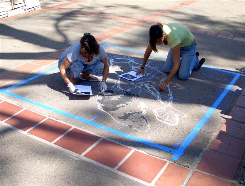 Artists beginning chalk street painting of koi